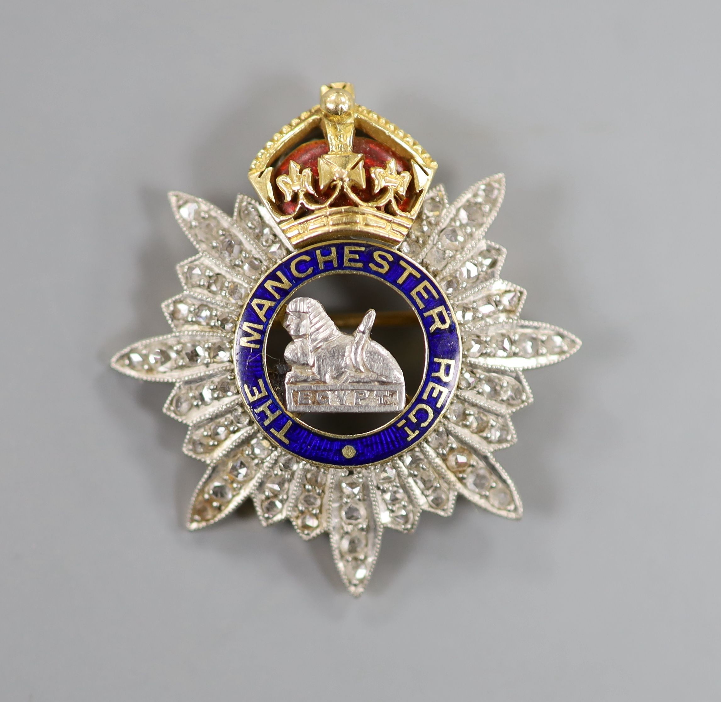 A late 19th/early 20th century yellow metal, enamel and rose cut diamond set 'The Manchester Regt. Egypt' pendant brooch, 32mm, gross weight 9.1 grams.